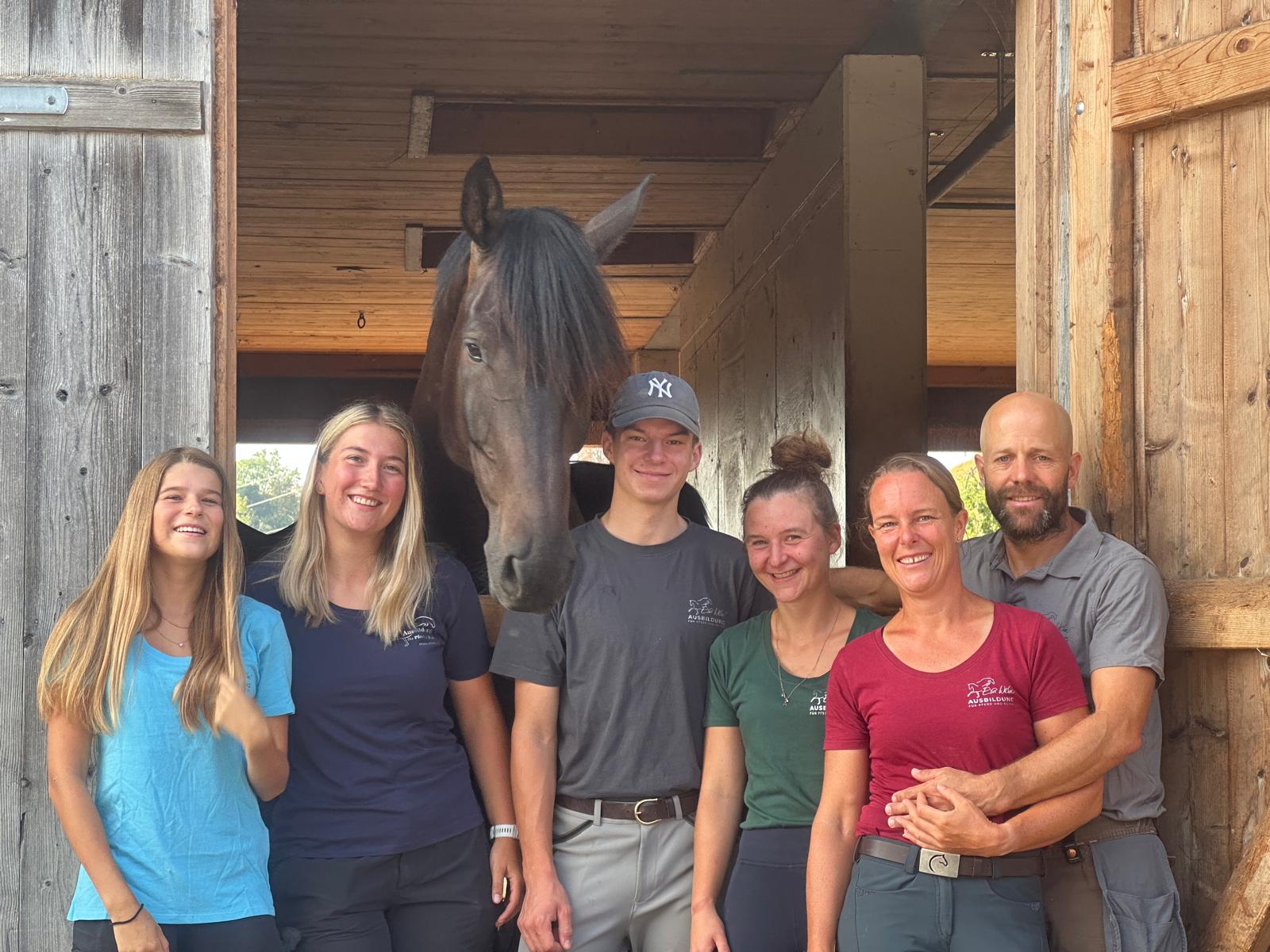 Teammitglieder mit einem Pferd im Hintergrund.